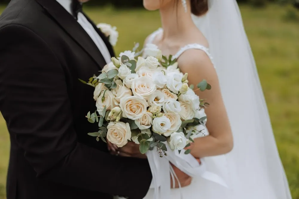 Bride holding a modern hand-tied wedding bouquet featuring seasonal flowers and silk ribbons