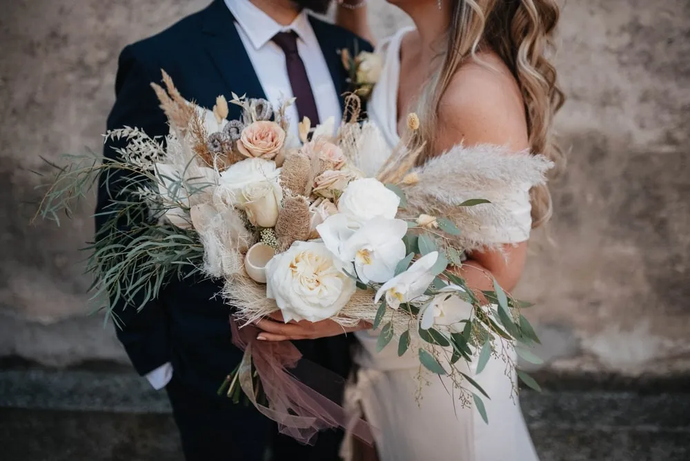 Bride holding a modern hand-tied wedding bouquet featuring seasonal flowers and silk ribbons