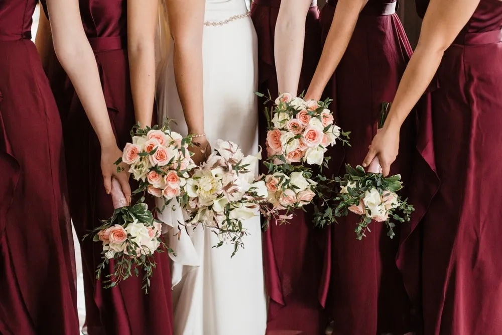 Bride holding a modern hand-tied wedding bouquet featuring seasonal flowers and silk ribbons